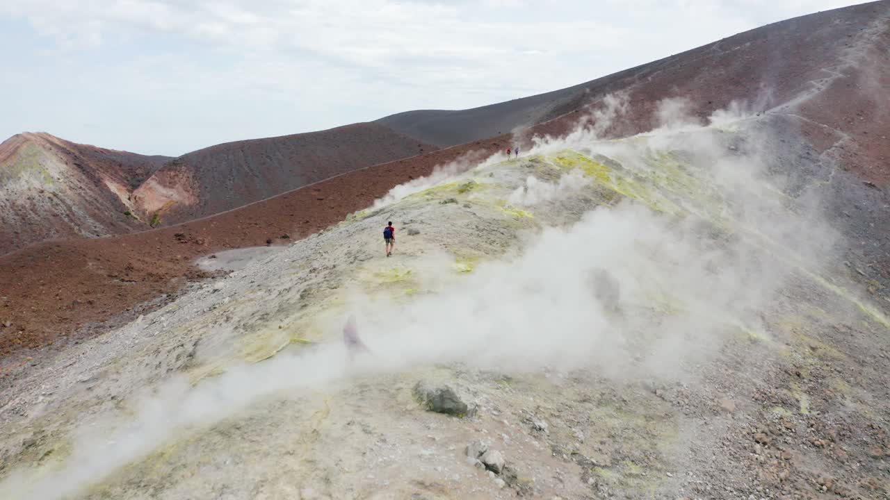 excursionistas masculinos y femeninos que viajan de senderismo en el volcán, caminando a través de humos sulfúricos. destino de viaje de la isla del volcán en sicilia, islas eolias.
