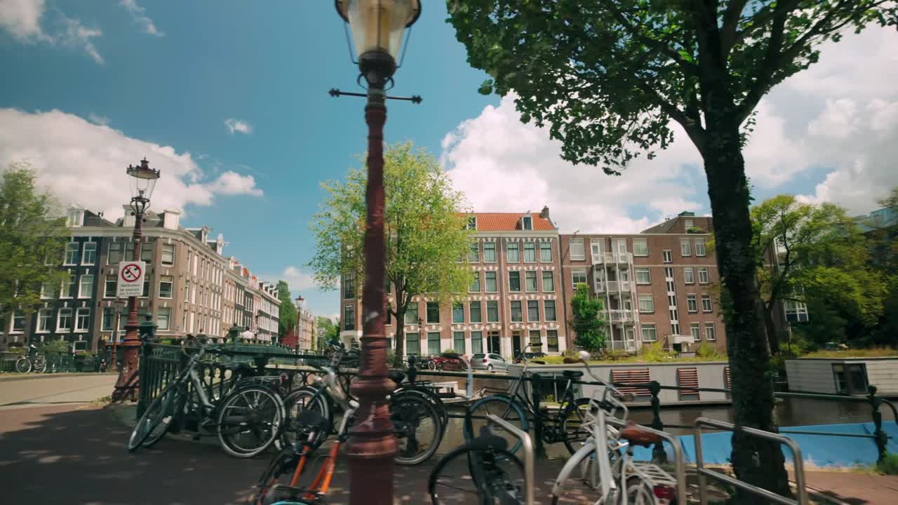 Sunny day view of an Amsterdam canal with historic buildings and bicycles