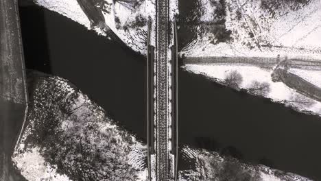 birds eye view of bridge with train tracks over a black river