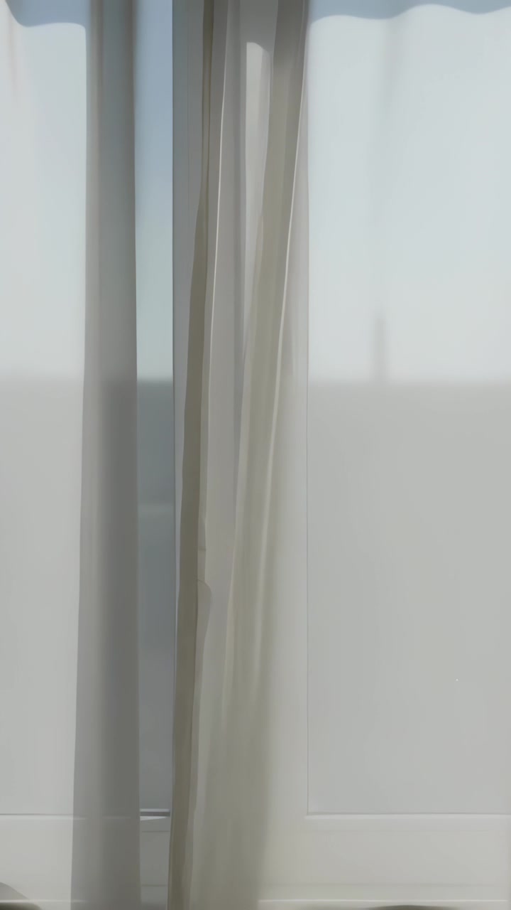 Vertical video: Shifting sheer curtain panel swaying left from breeze at glass door, revealing rail