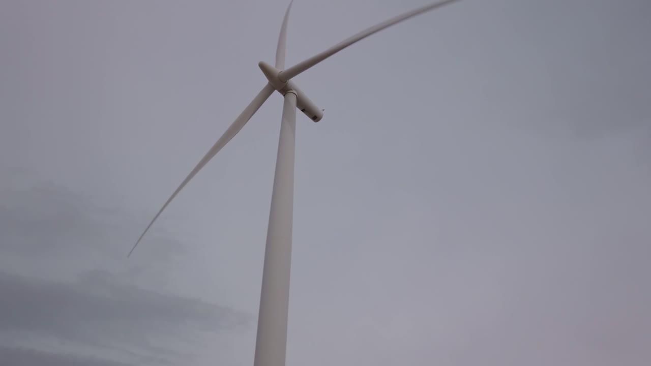 Rotating Wind Turbine Against Cloudy Sky