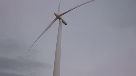 rotating wind turbine against cloudy sky