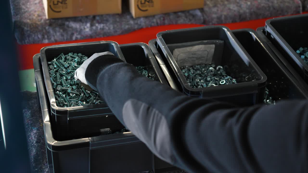 공장에서 작업을 준비하기 위해 상자에서 나사를 집어드는 사람