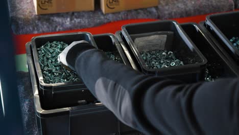 persona recoge tornillos de una caja en preparación para el trabajo en una fábrica