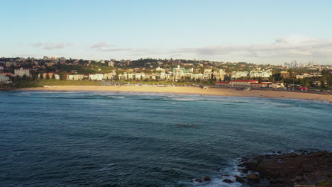 Drone-Volando-Hacia-La-Playa-Bondi-Durante-La-Hora-Dorada-De-La-Mañana,-Sydney-Australia