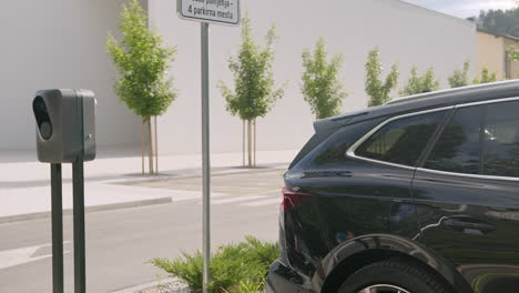 Girl-plugging-cable-charger-into-her-electric-car-on-parking,-handheld-shot