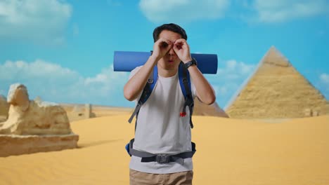 asian male hiker with mountaineering backpack making binoculars gesture looking at something then saying wow while traveling in pyramid of giza