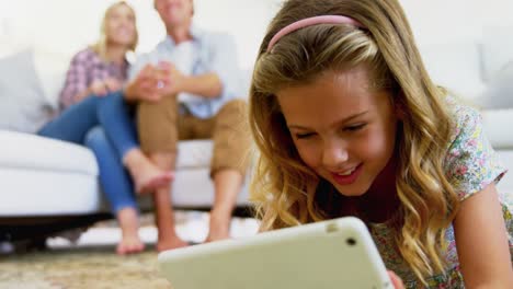 daughter using digital tablet in living room while parents sitting on sofa 4k