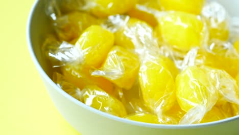 Close-up-of-lemon-candy-in-a-bowl-on-yellow-background