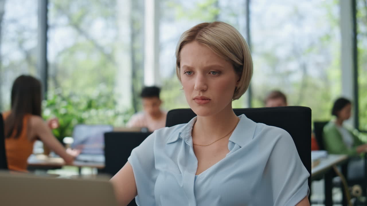 Nærbilde av en seriøs kvinne som lytter til en videosamtale på laptop på kontoret. Forretningskvinnen er enig.