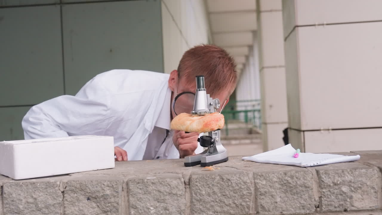 Scientific researcher in white coat rises up carefully observing pastry with microscope outdoors, reflecting curiosity, focus, and dedication to experimental scientific study with notebook and pen