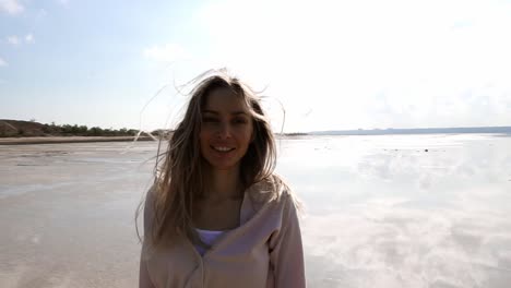 retrato de una niña sonriente caminando por la orilla del lago, mirando pensativo a la cámara