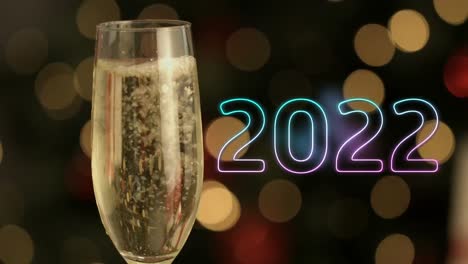 Animation-of-2022-text-over-glass-of-champagne