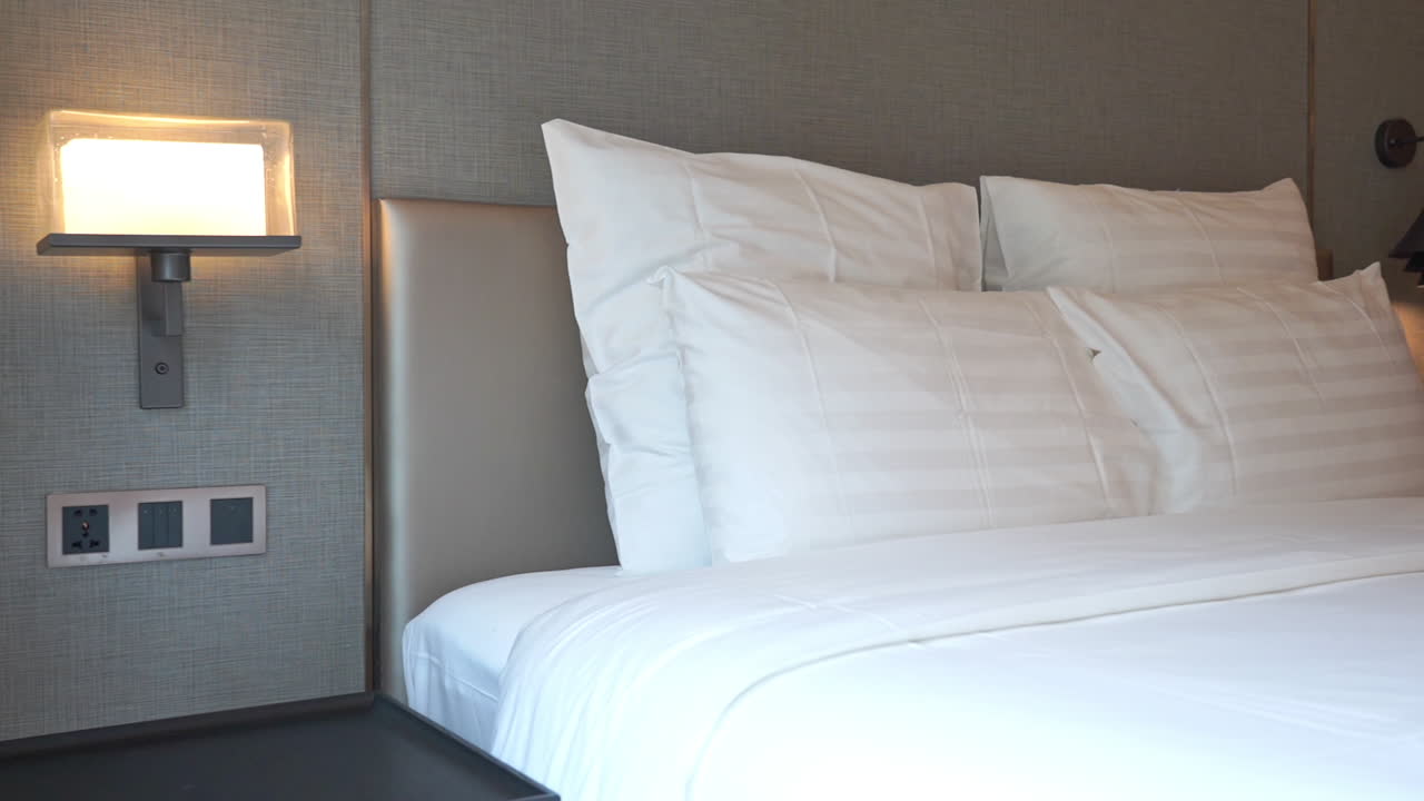 하얀 솔직한 시트와 베개가 있는 우아한 더블 침대