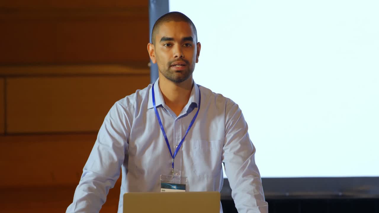 Male speaker with laptop speaking on stage in auditorium 4k