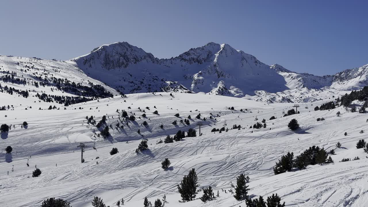 Andorra'daki Grandvalira kayak merkezinin üzerinde 4K sinematik drone havadan çekim, berrak bir kış güneşinin altında geniş karlı dağ sıralarını ve yoğun alpin ormanlarını gözler önüne seriyor.