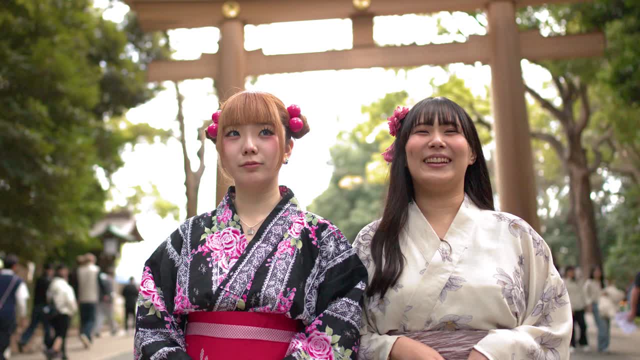 Due donne che indossano kimono tradizionali stanno insieme all'ingresso di un santuario sotto una luce soffusa.