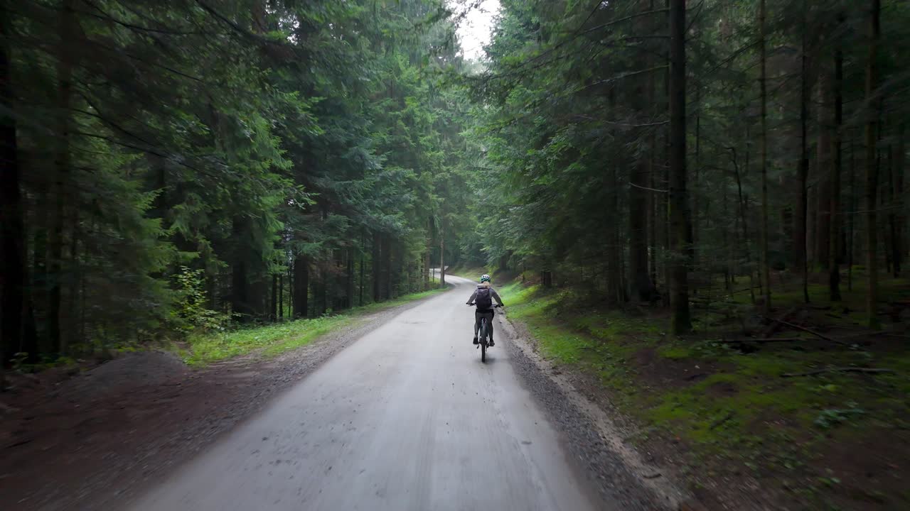 Woman rides e-bike through peaceful forest trail, surrounded by lush greenery and nature—ideal for outdoor, travel, wellness, and active lifestyle concepts