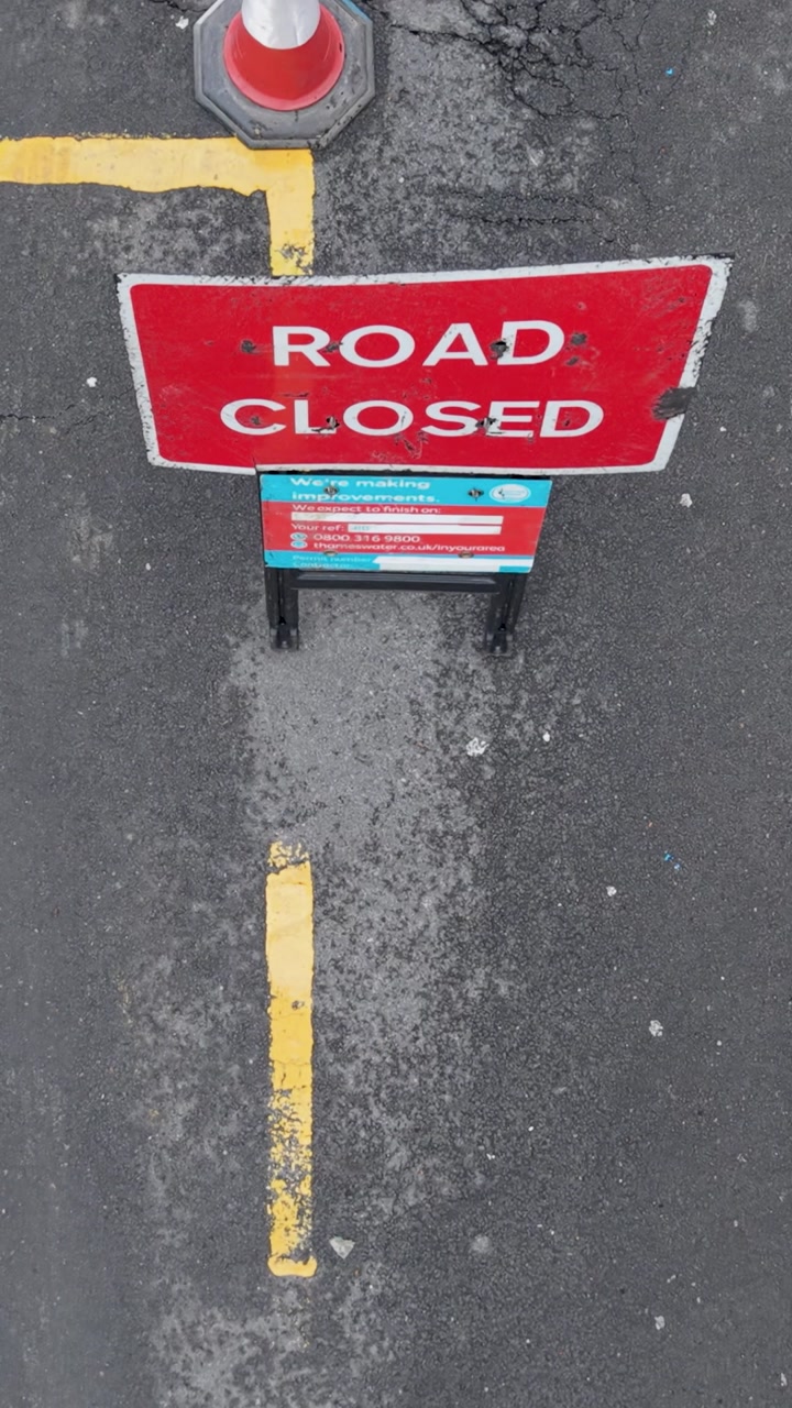 Vertical drone flight over road markings, “Road Closed” sign, barriers