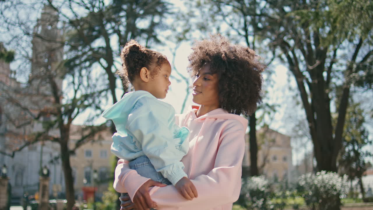 mamá sosteniendo a su hija de pie en el callejón del parque de cerca. caminata de fin de semana
