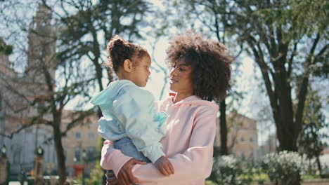 mom holding daughter standing on park alley close up. weekend walk