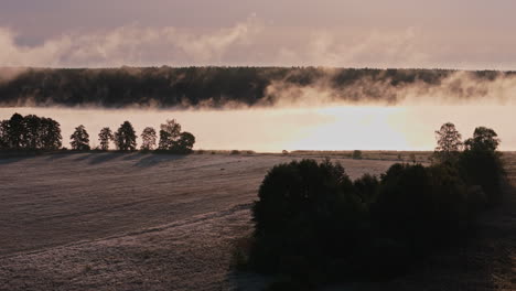 misty sunrise over a frozen field and lake