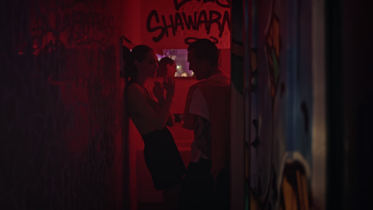 Cute couple engaged conversation in graffiti-adorned alley. Romantic interaction