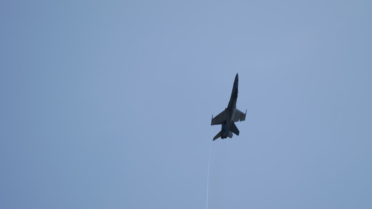 Fighter jet executing dynamic aerial maneuvers, showcasing agility and power against a clear blue sky