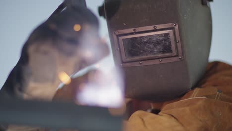 welder in full mask and protective gear close up,sparks in slow motion