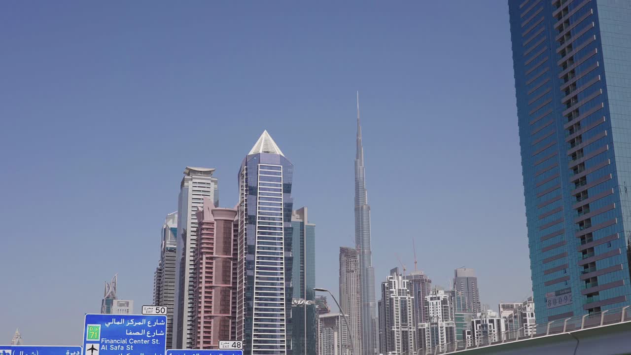 Burj Khalifa e grattacieli e torri di Downtown Dubai, vista dall'autostrada e da un veicolo in movimento.