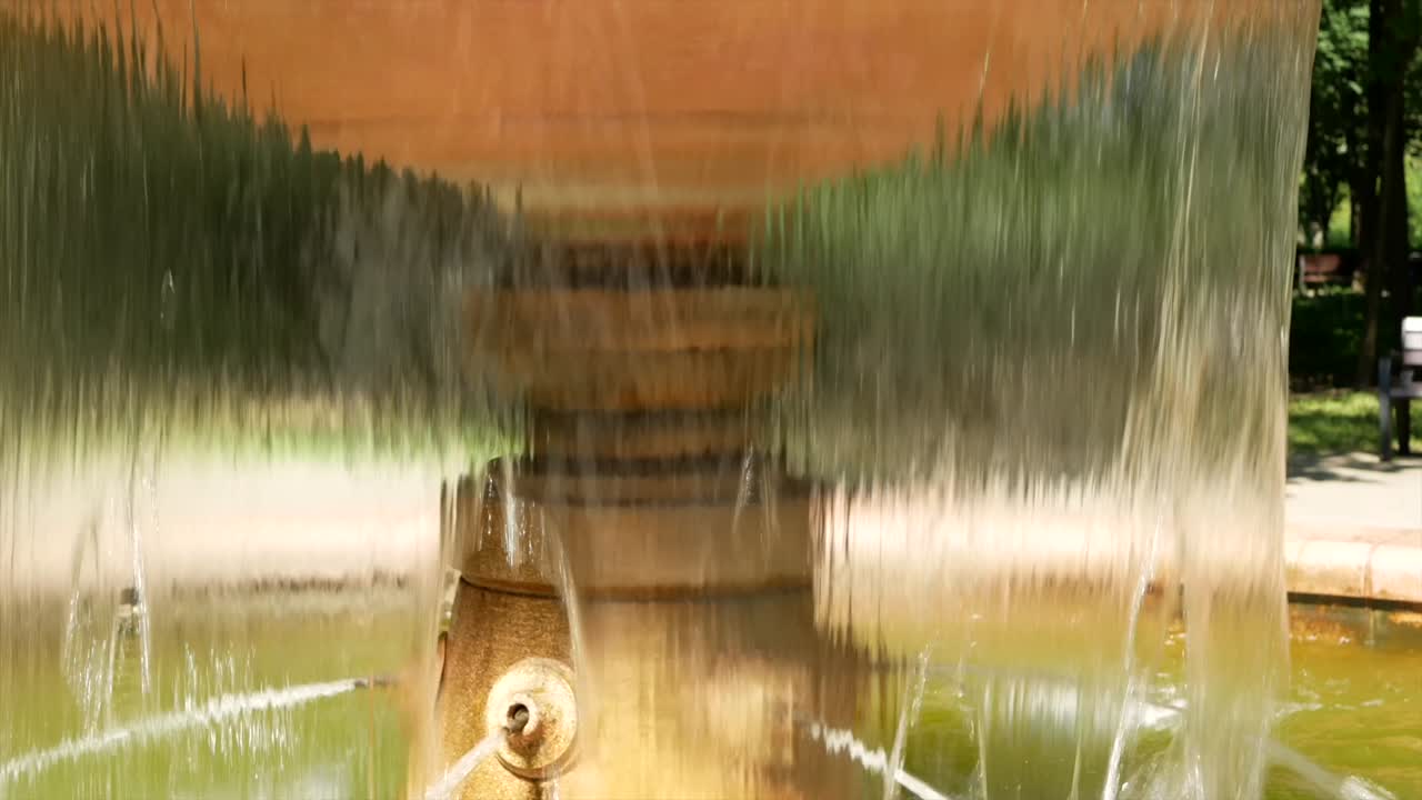A small fountain with water in the summer park - a place of rest from the heat