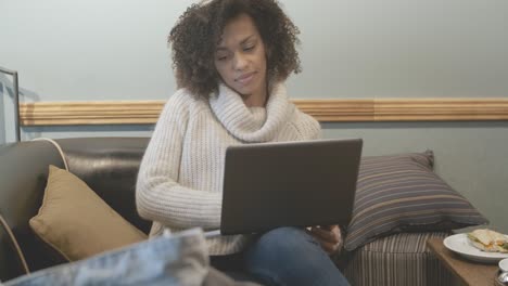 mujer estudiante casual sentada en una cafetería y usando una computadora portátil