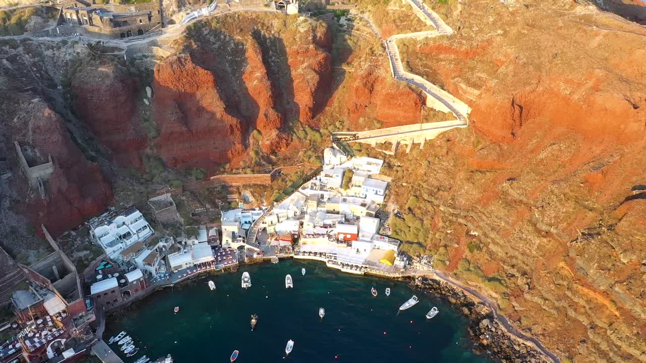 video aéreo del famoso pueblo pintoresco encalado y colorido de oia construido sobre un acantilado durante la puesta de sol, isla de santorini, cícladas, grecia