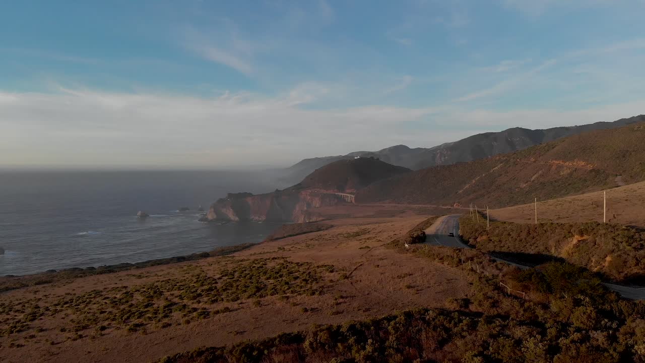 coches conduciendo por la soleada carretera costera uno cerca de la costa rocosa en el norte de california