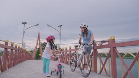 mother and daughter cycling on a bridge