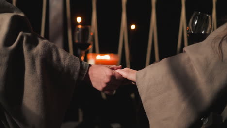 man strokes woman hand closeup. husband prepares romantic dinner for wife with wine in autumn evening during vacation. candlelight dinner on terrace