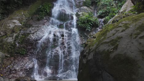 Rise-from-large-moss-covered-boulder-at-Marinka-Waterfall-in-Minca-Colombia