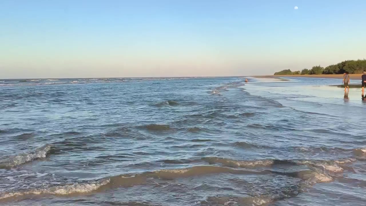 Onde leggere che si infrangono su una spiaggia sabbiosa al tramonto