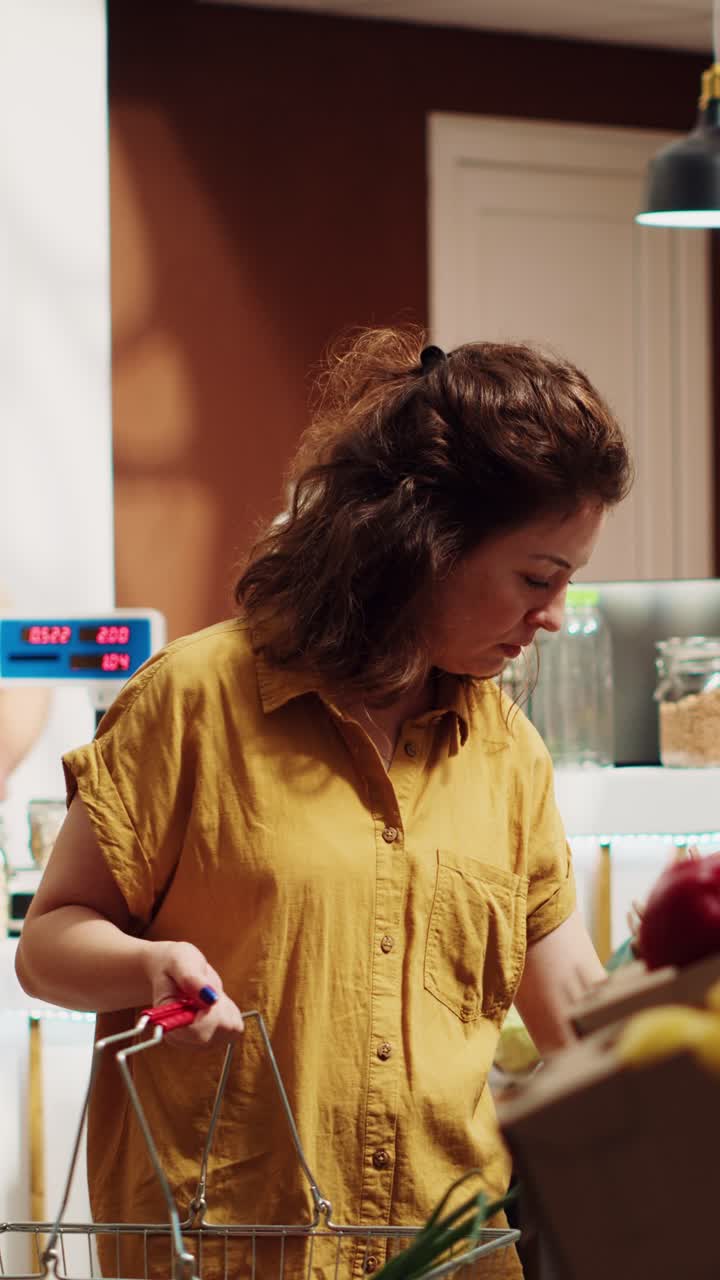 Vídeo vertical: mujer añadiendo comida saludable a la cesta de la compra