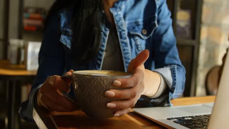 vista frontal de una joven de raza mixta bebiendo café en la mesa en el café 4k