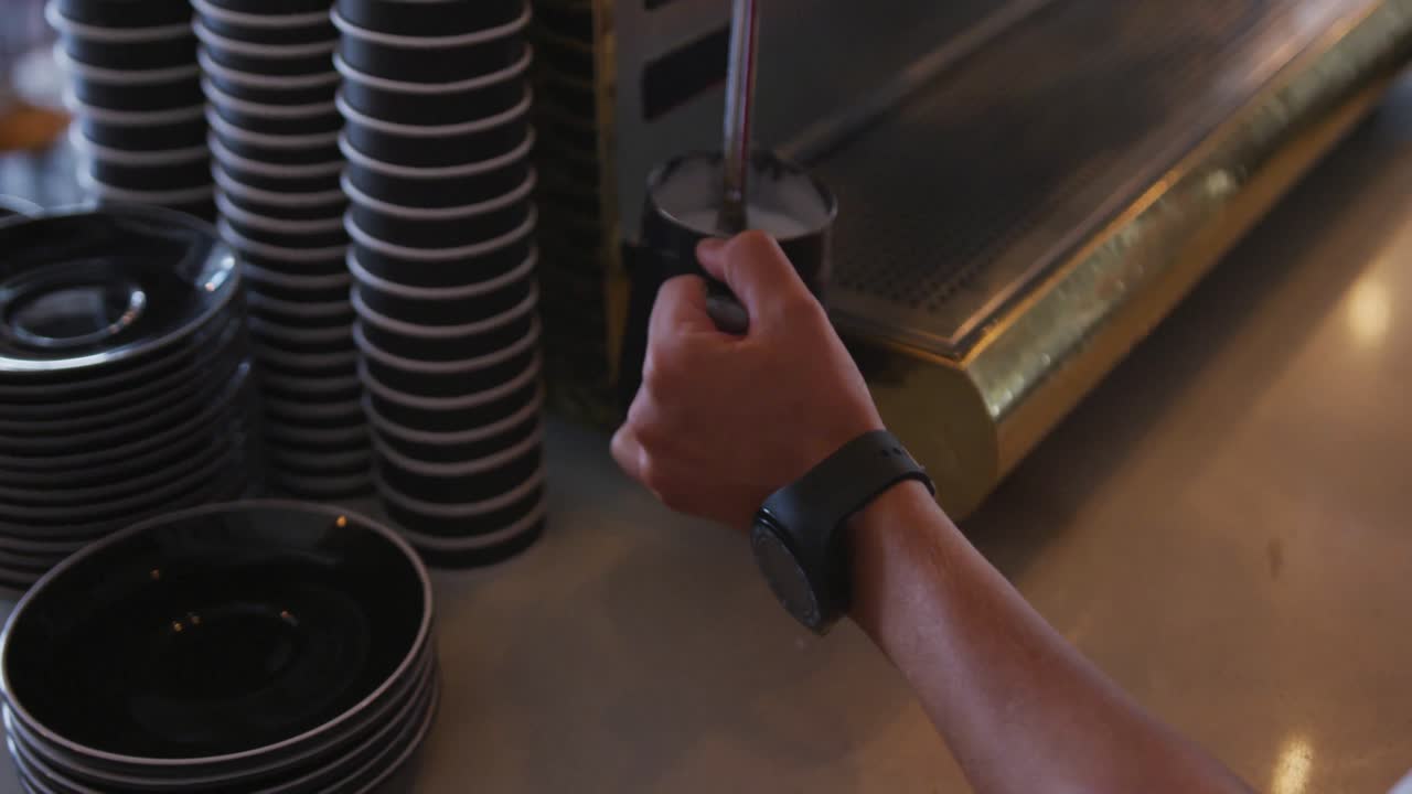 Hands of mixed race male barista wearing an apron preparing takeaway coffee