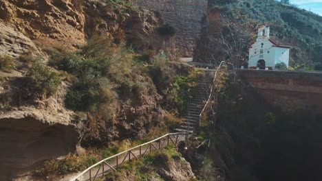 aerial view of a hiking path coming from a bridge and a catholic hermitage over a ravine in spain