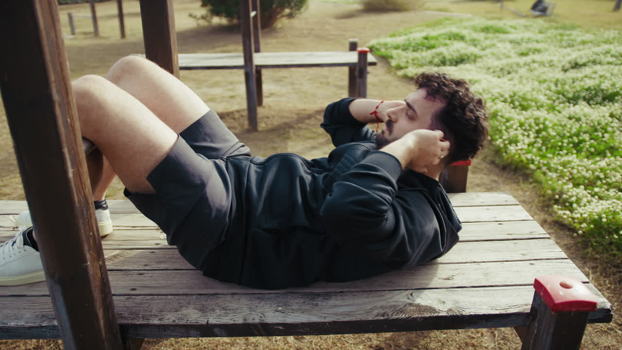 Man Trains on a Wooden Bench in the Outdoor Park