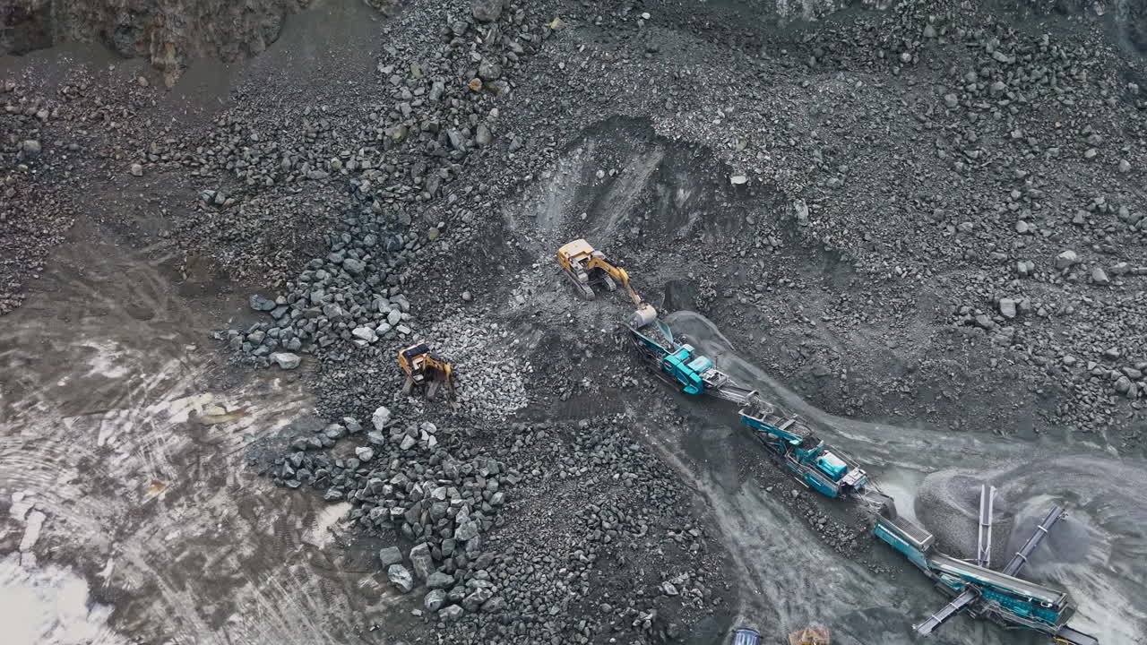 Granite quarry operation in a rock-filled area with machines and workers actively extracting stones