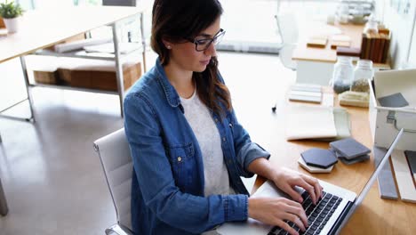 ejecutiva sentada en un escritorio y usando una computadora portátil