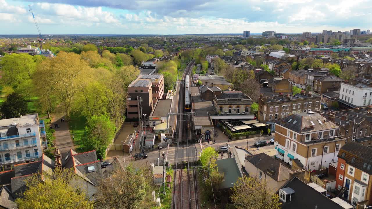 Ripresa con drone che sorvola i binari ferroviari in una verdeggiante cittadina rurale britannica.