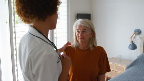 female nurse wearing uniform giving senior female patient bad news in private hospital room