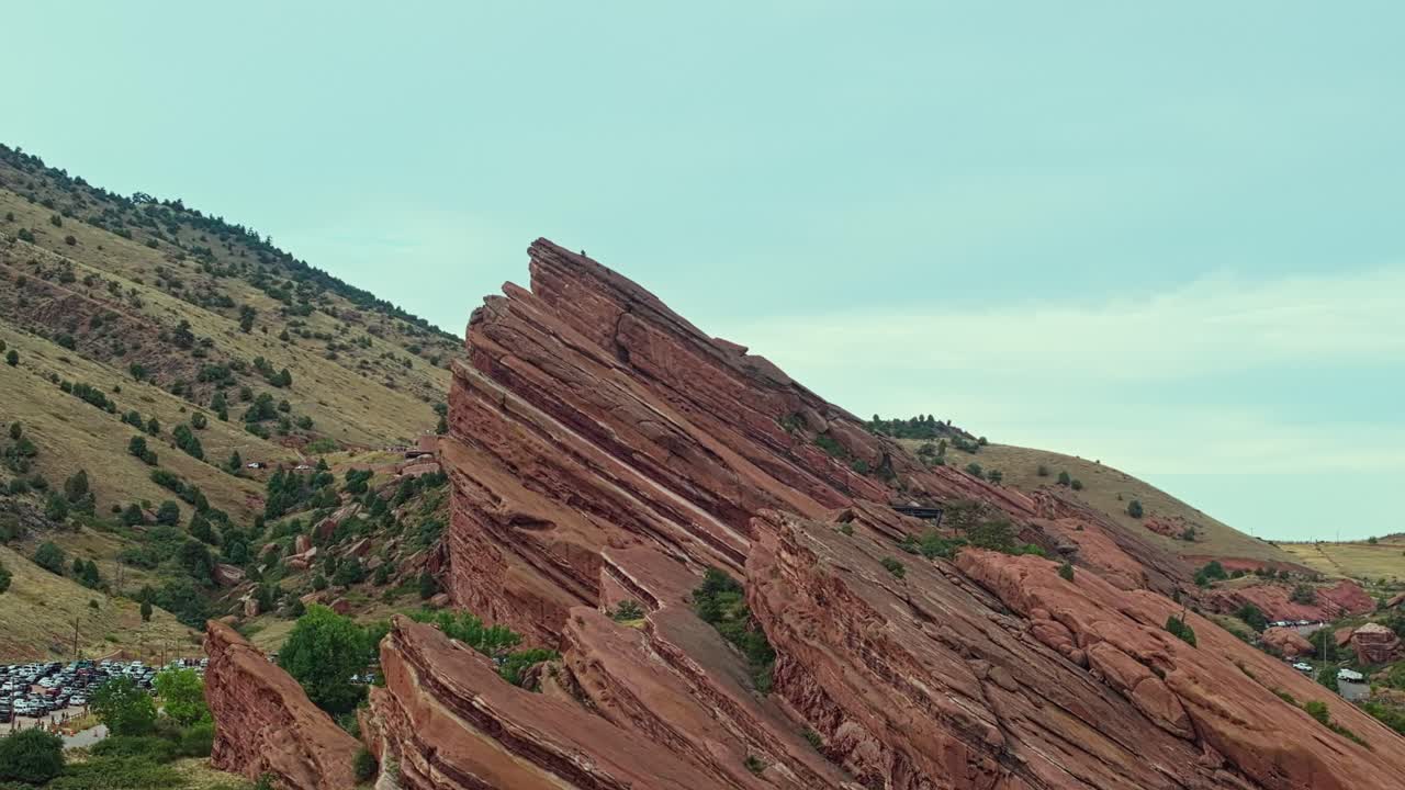 Drone orbit above Red Rocks Amphitheatre showing sweeping desert terrain and vivid red sandstone peaks in sunlight