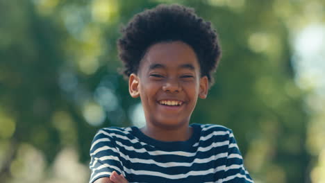 portrait of laughing young boy standing outdoors in summer garden park or countryside