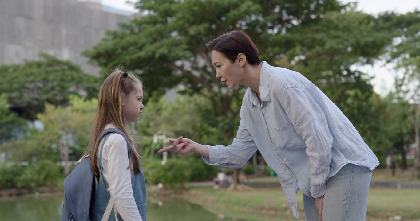 แม่กำลังว่ากล่าวลูกสาวด้วยสีหน้าจริงจังในสวนสาธารณะ